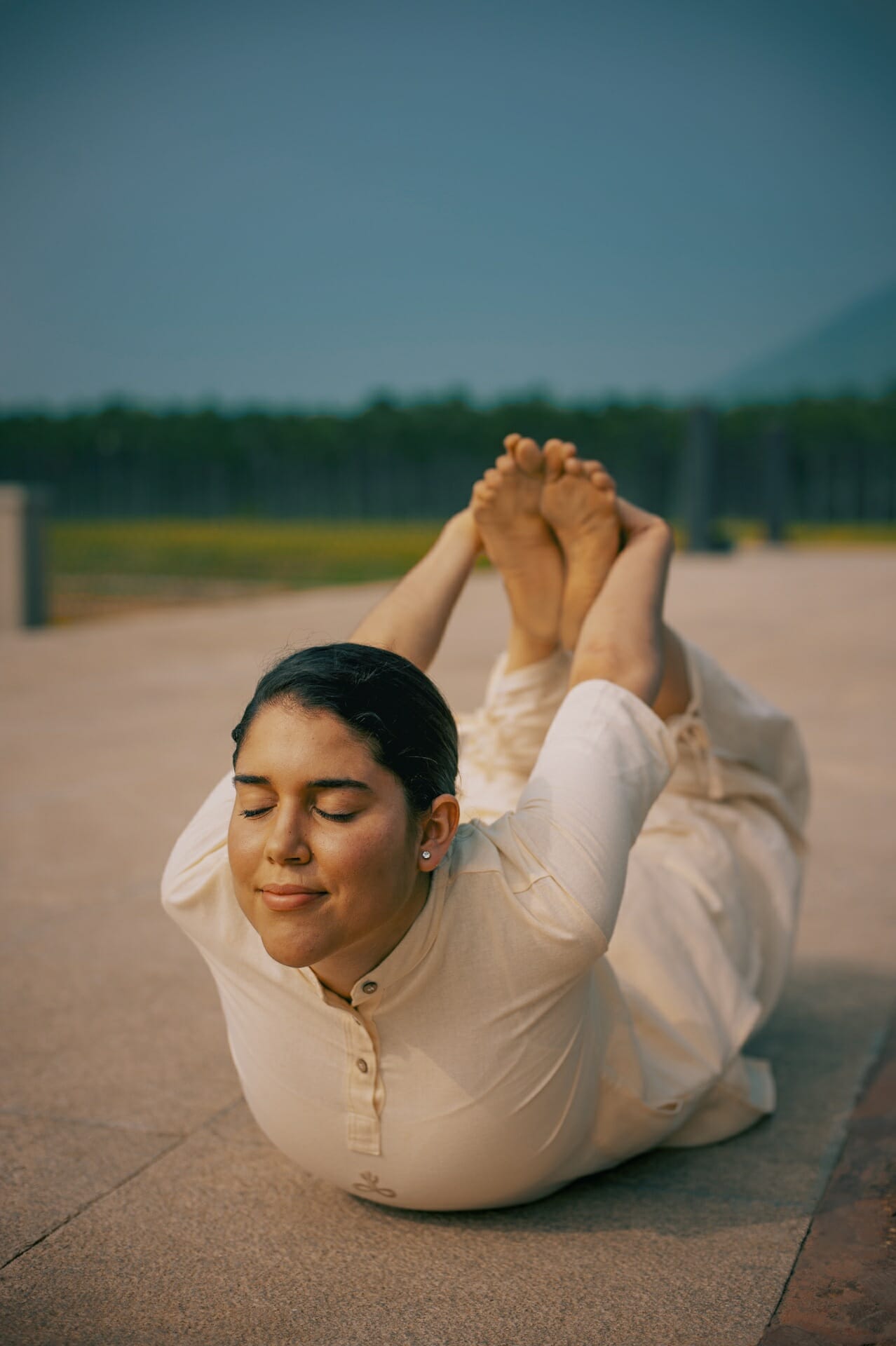 A woman doing a yoga pose on the ground in India.