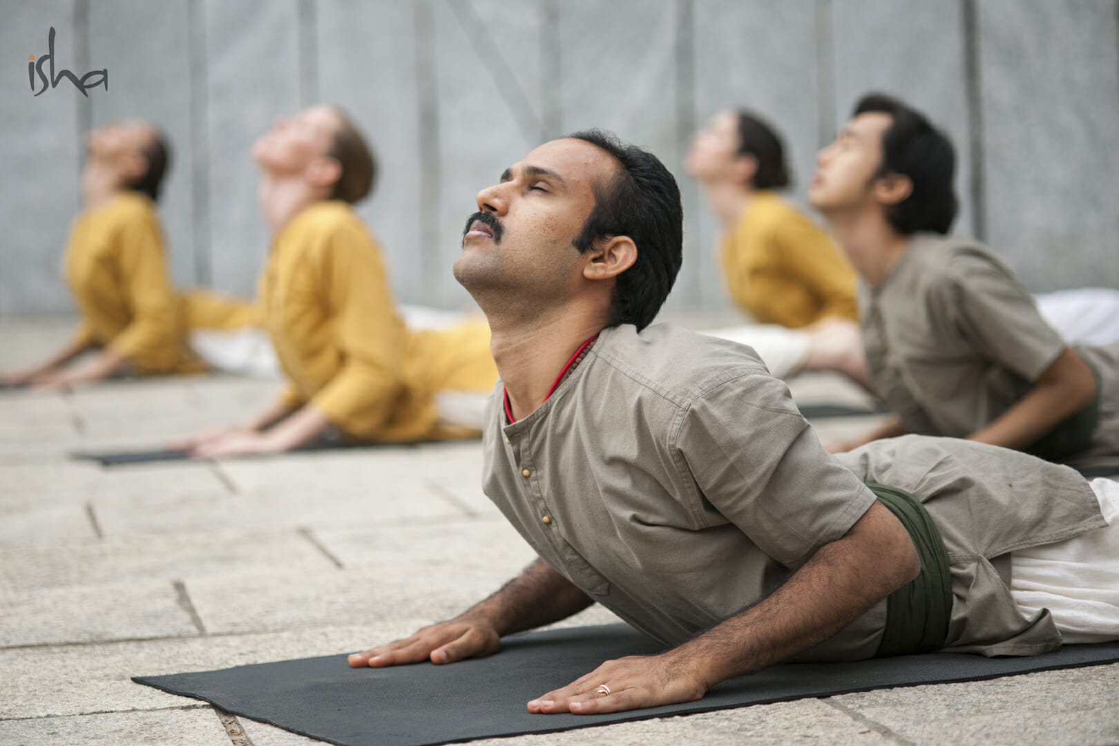 A group of men doing yoga on a mat.