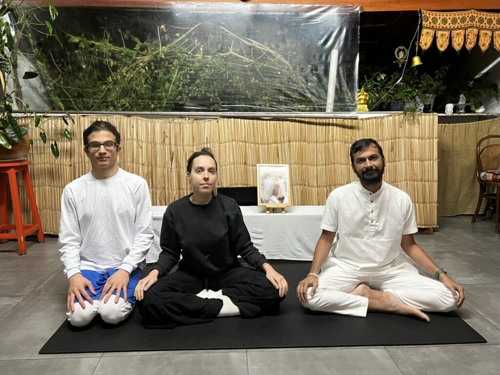 Three people sitting on the floor in front of a wall.