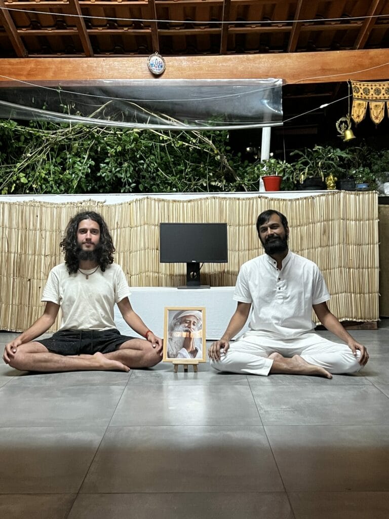 Two men meditating on the floor in front of a picture.