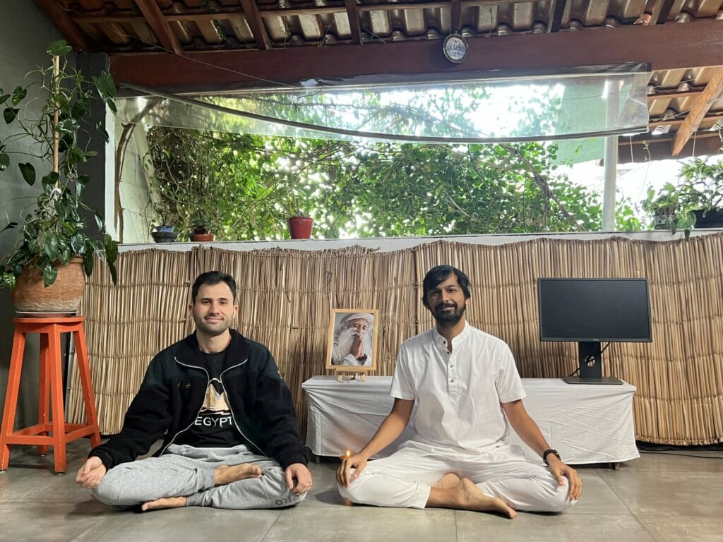 Two men meditating in front of a window.