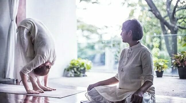 A woman doing yoga on a mat in front of a window.